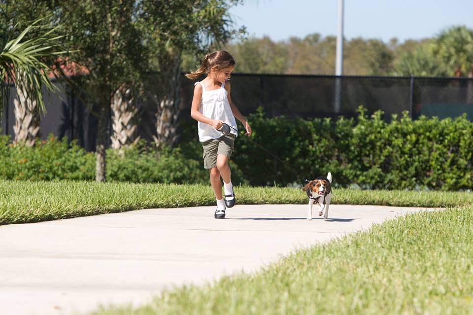 Young girl running with dog in Ave Maria park Young girl running with dog in park