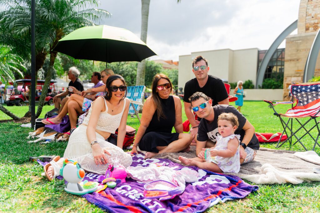 Family attends 2024 Margarita & Taco Festival in Ave Maria, while sitting on the grass with a planned picnic
