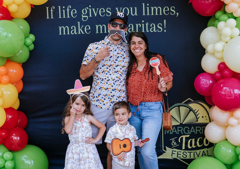 Family pose with props at photo backdrop at Ave Maria Margarita & Taco Festival