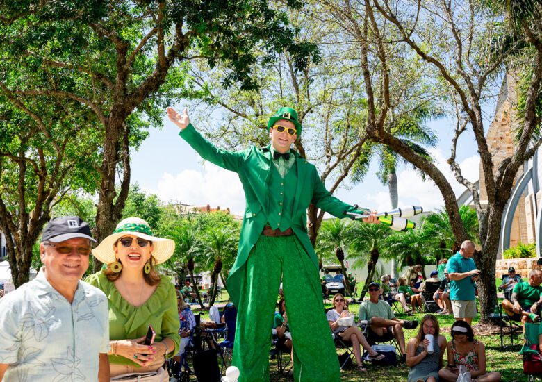 Stilt walker poses for photo with couple at 2026 Shamrock Festival in Ave Maria Town Center